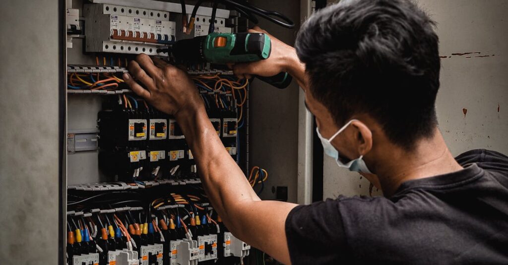 Technician working on circuit breaker panel, adjusting electrical wires indoors.